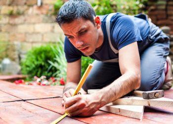 Man med verktyg i trädgården som bygger ett växthus